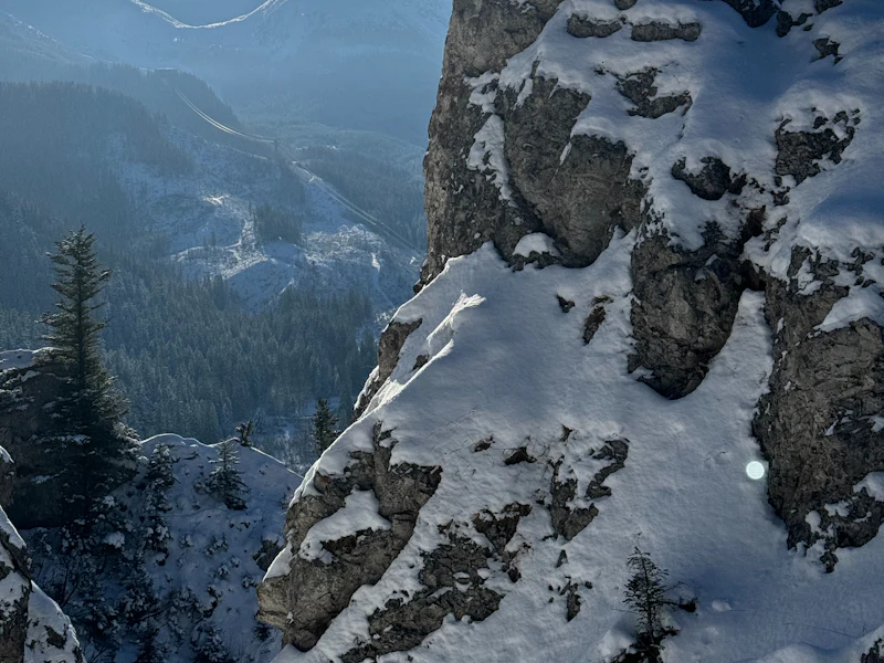 Snow on a rocky mountain with a valley below